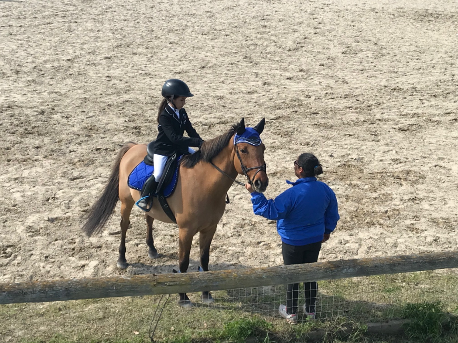 Giovane amazzone a cavallo seguita dall’istruttore durante allenamento