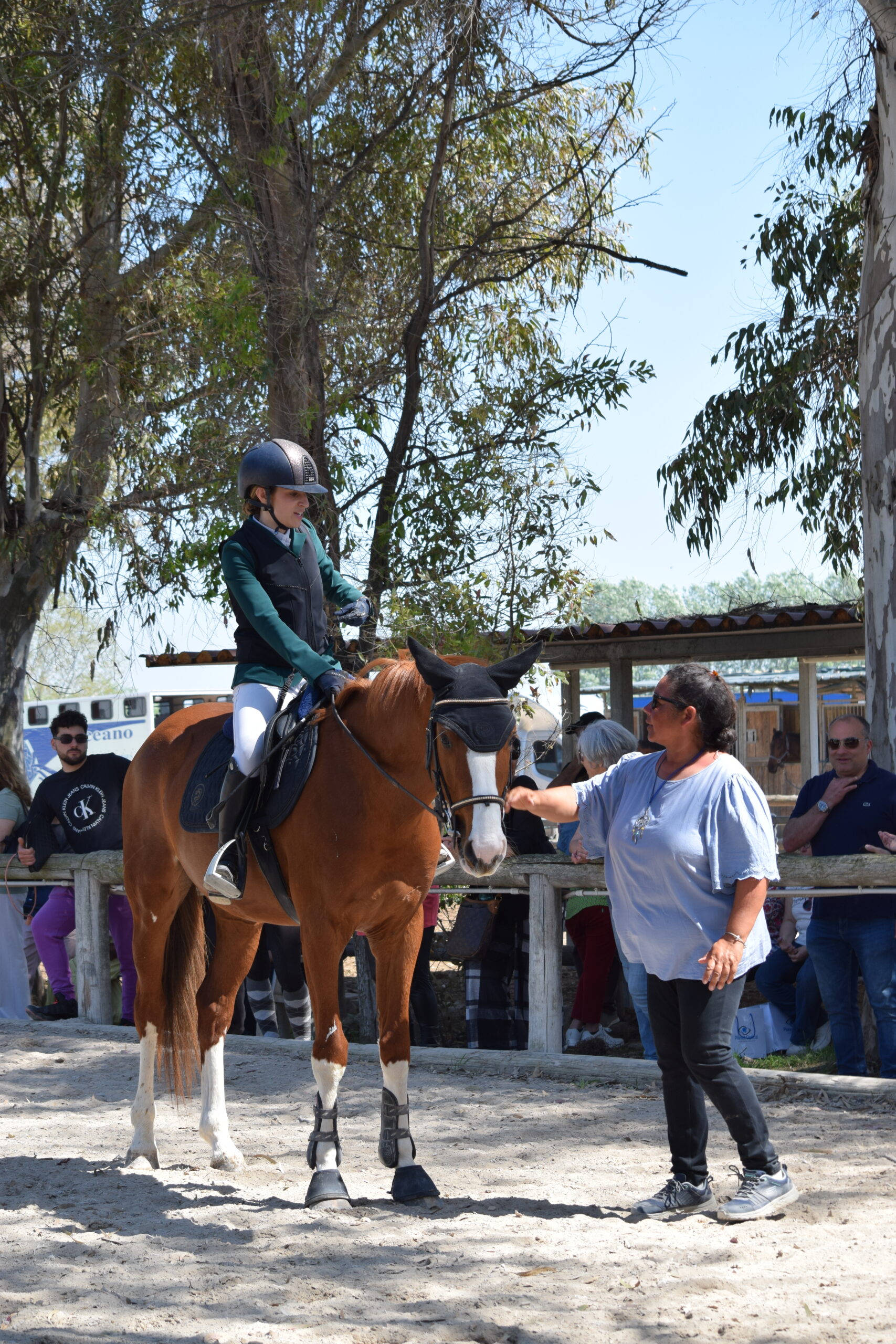 Allieva a cavallo riceve indicazioni dall’istruttrice durante una lezione di equitazione