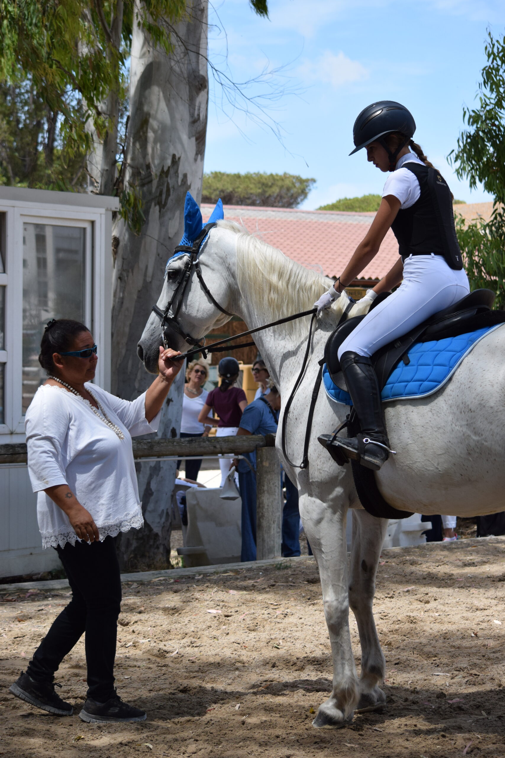 Cavallerizza su cavallo bianco parla con l’istruttrice prima della lezione di equitazione al Vinci Jumping Team
