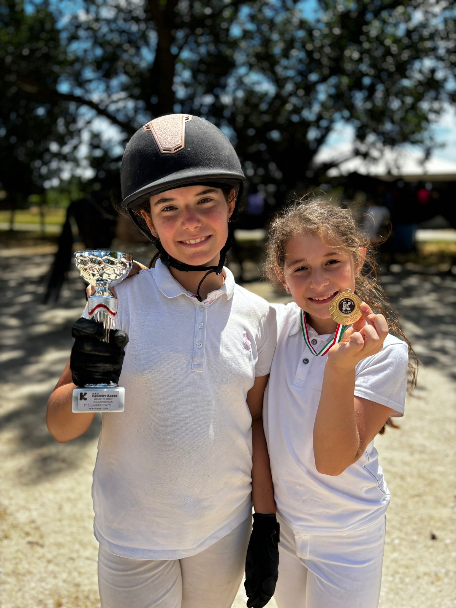 Bambine con medaglie e coppa dopo gara di equitazione pony