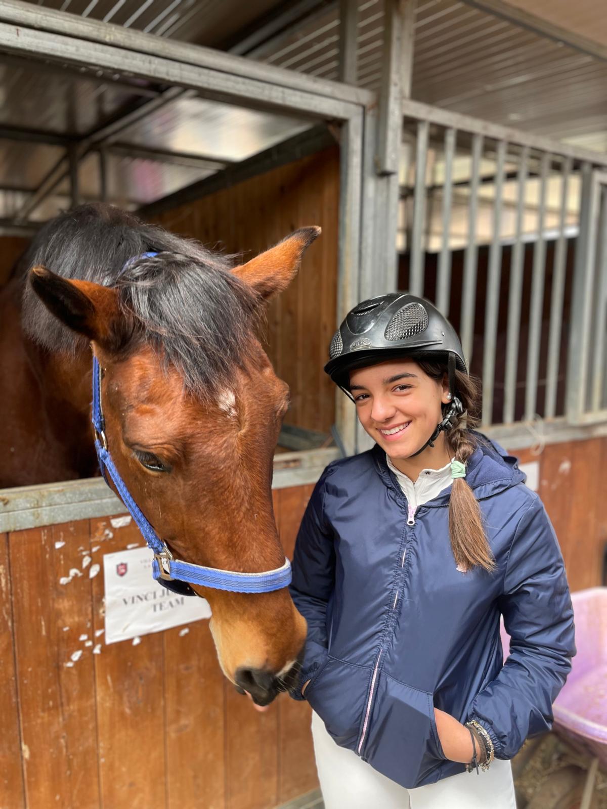 Ragazza accanto al cavallo nel box del maneggio