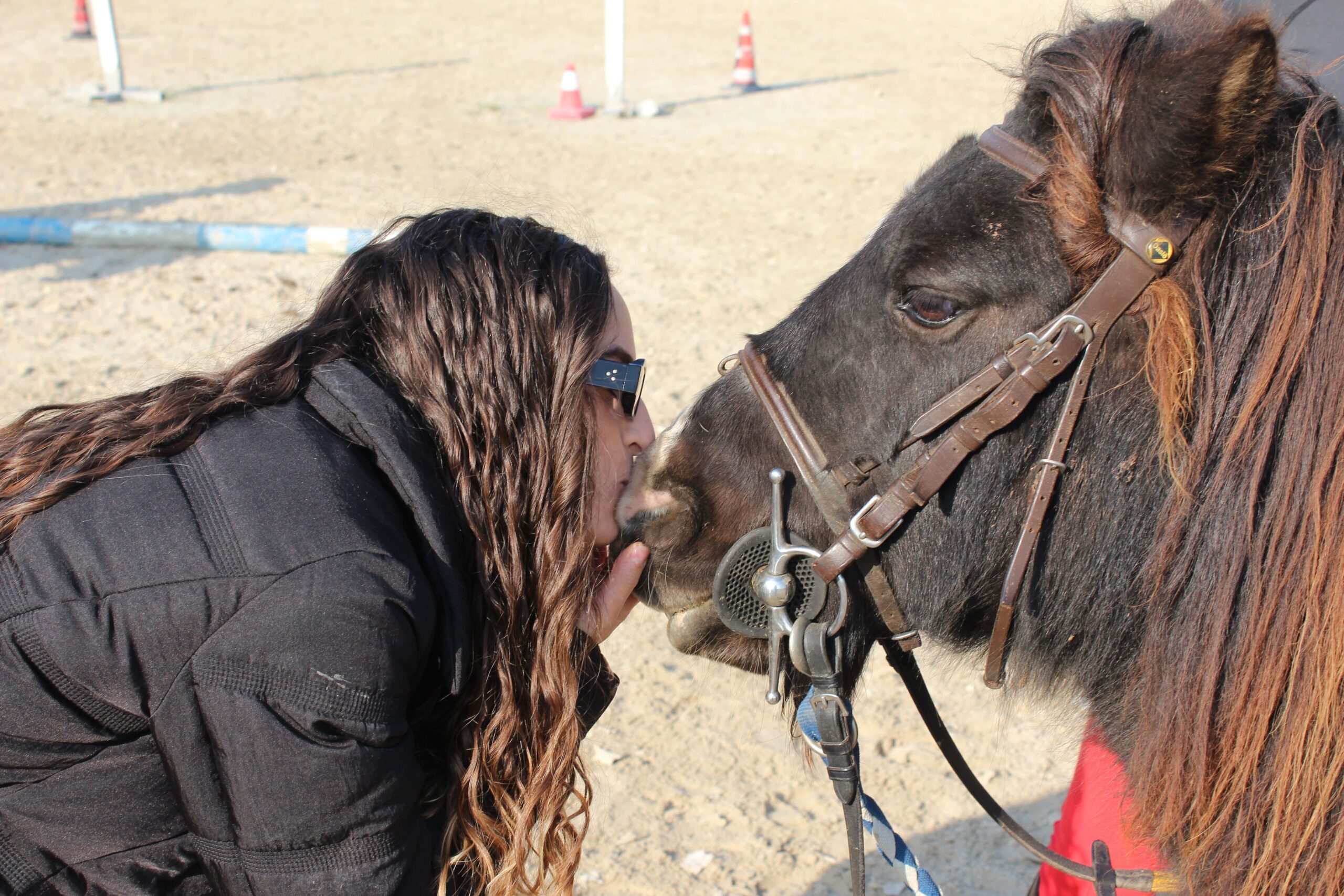 Ragazza che saluta il pony nel campo del centro ippico