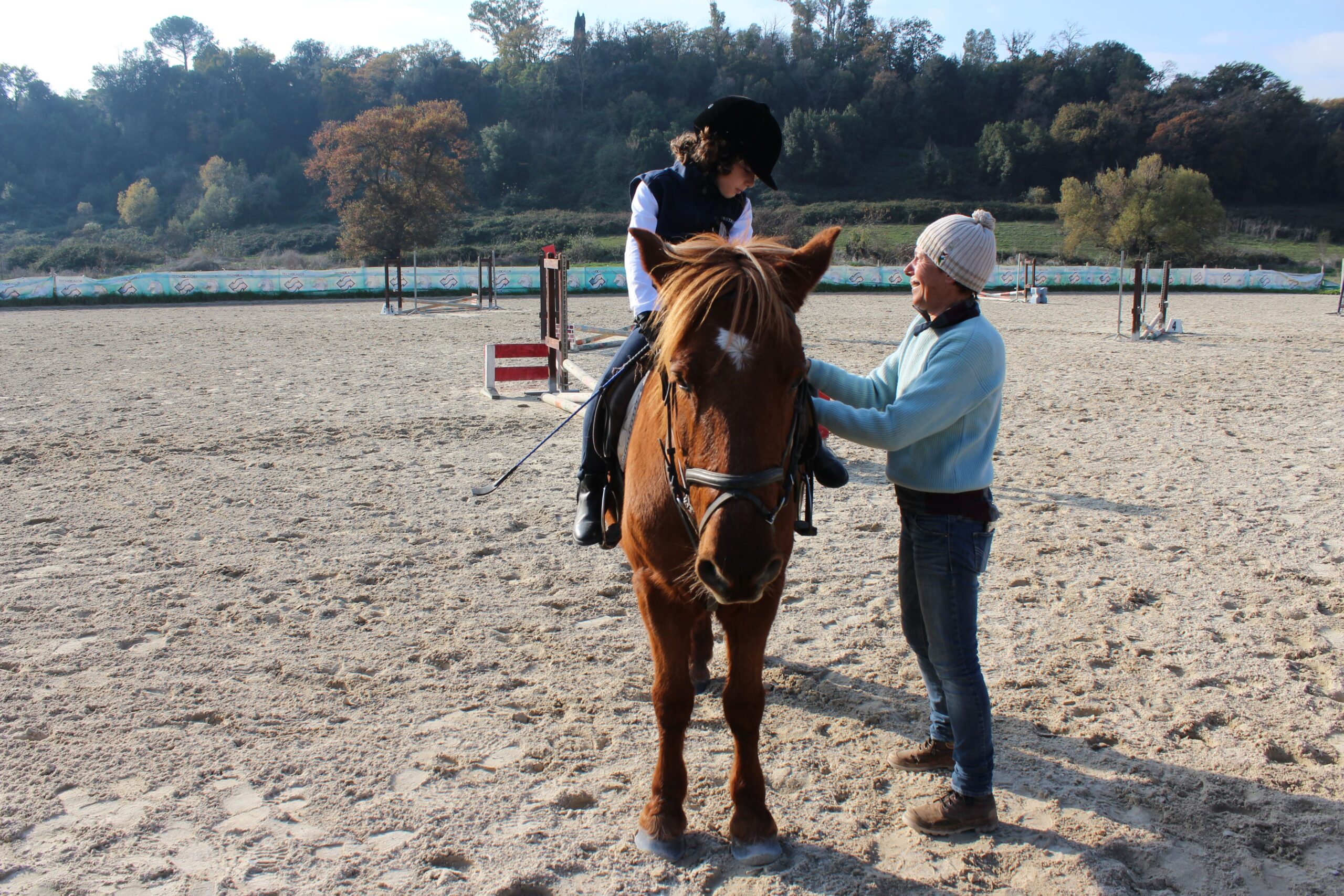 Istruttore che aiuta una giovane amazzone a cavallo durante la lezione