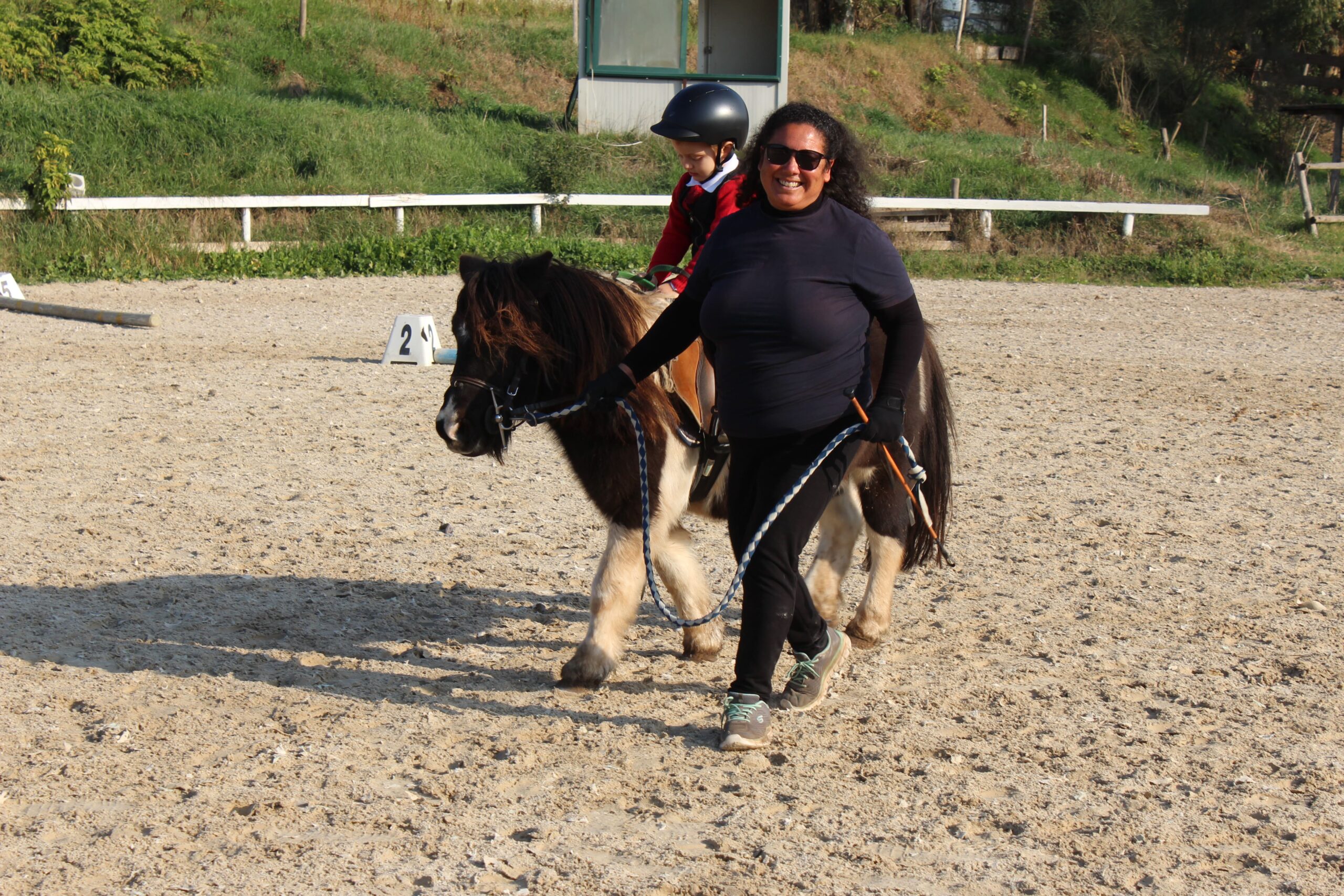 Bambina su pony accompagnata dall’istruttrice durante lezione di equitazione