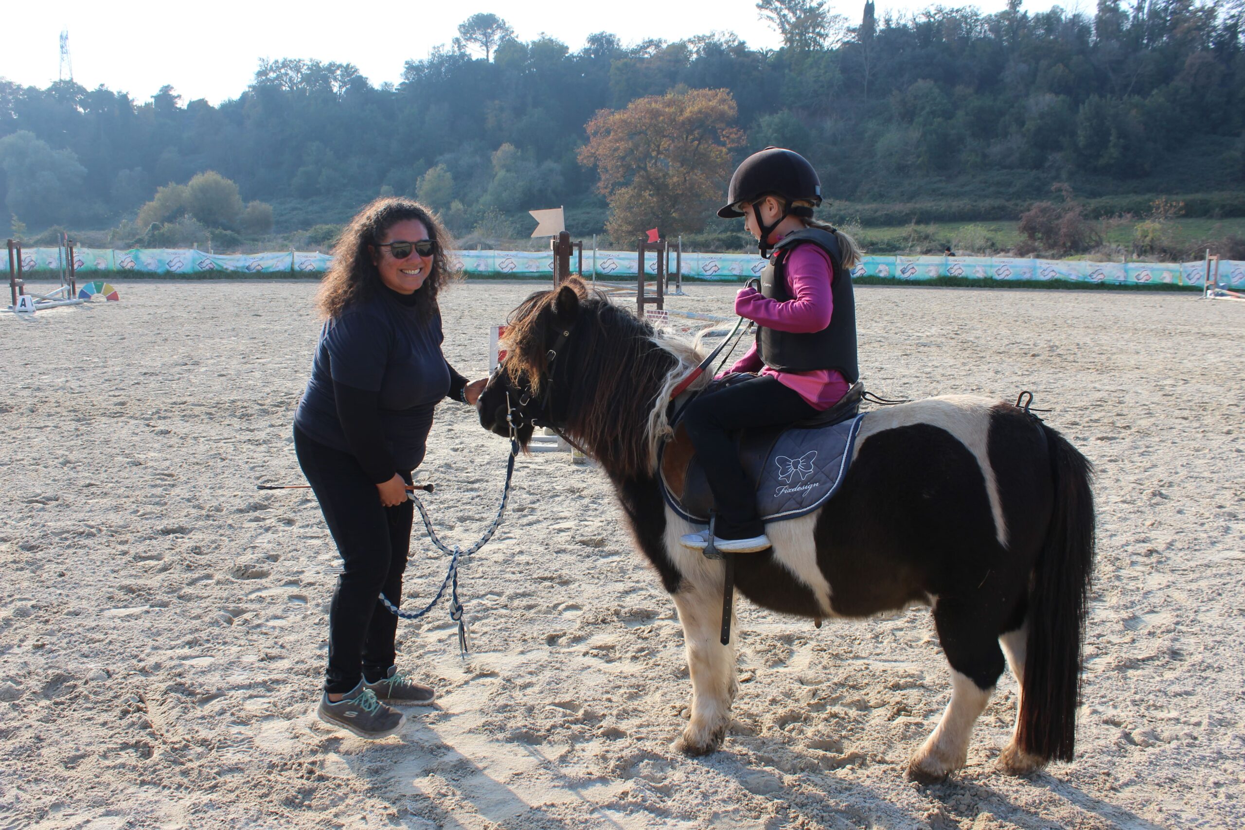 Bambina su pony durante lezione seguita dall’istruttrice