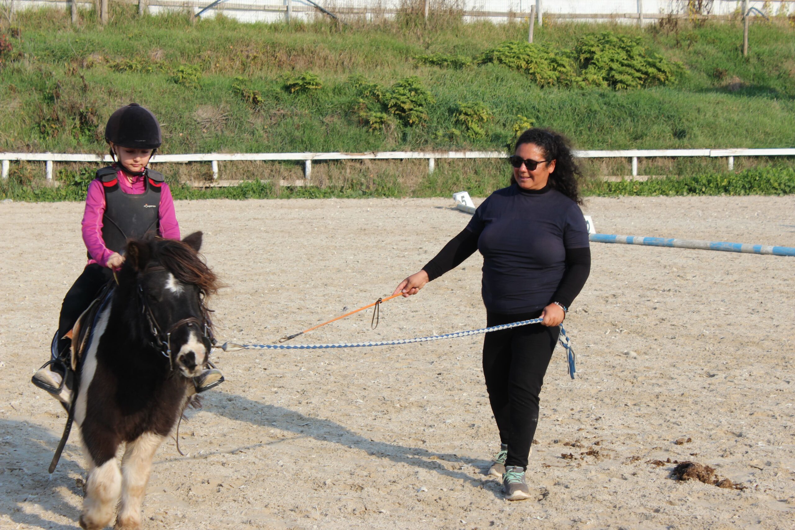 Istruttrice conduce un pony con un’allieva durante una lezione di equitazione nel maneggio Vinci Jumping Team