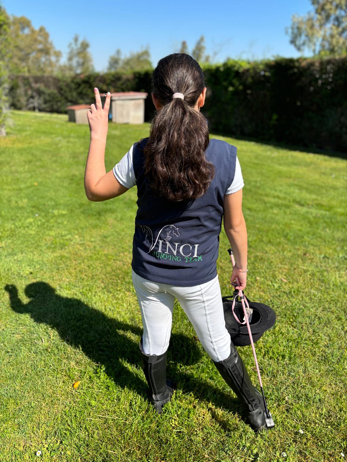 Ragazza con abbigliamento da equitazione alza la mano durante attività nel centro ippico Vinci Jumping Team