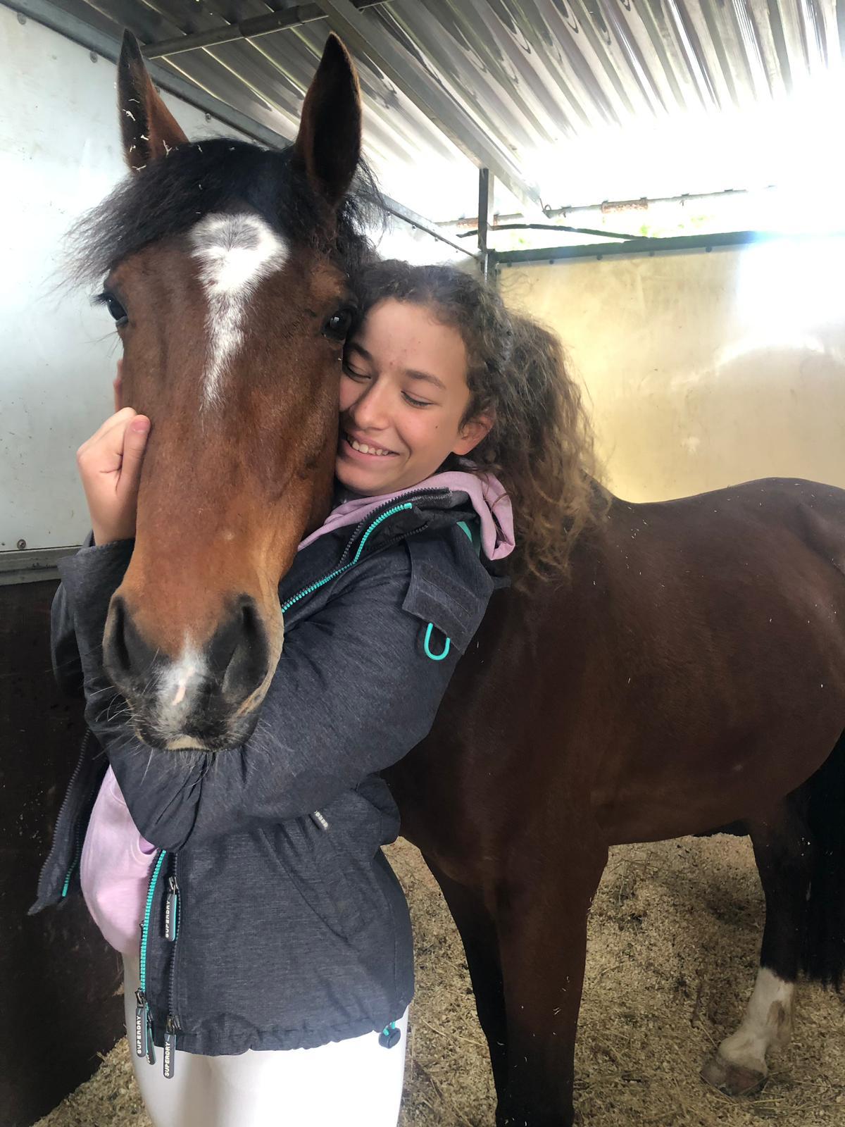 Ragazza che abbraccia il cavallo nella scuderia