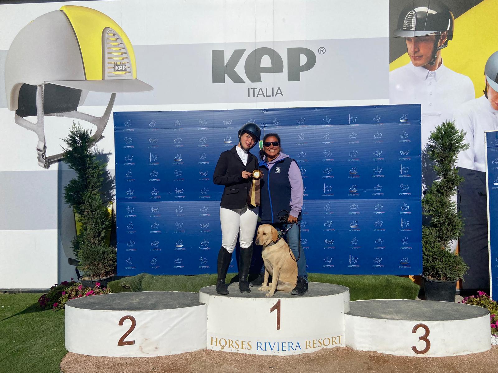Amazzone premiata sul podio con istruttore durante concorso di salto ostacoli