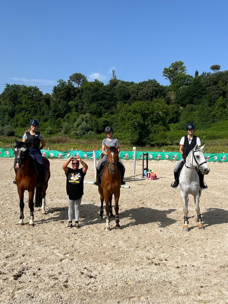 Allieve a cavallo durante una lezione di equitazione nel campo di un centro ippico